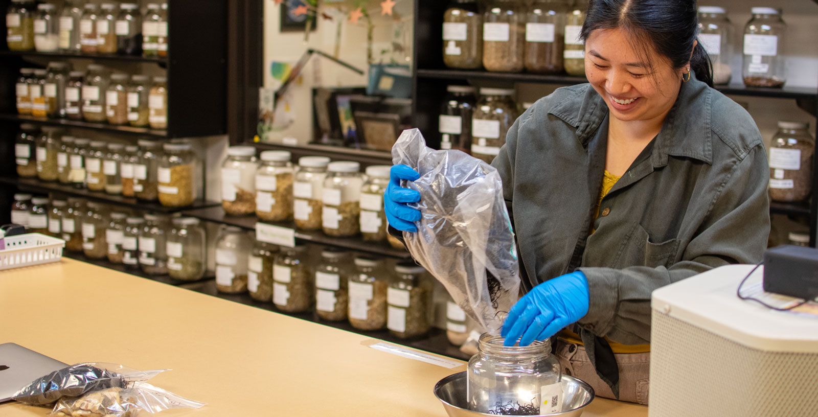 woman pouring herbs into jar